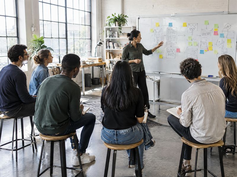 Instructor at a whiteboard of user flows while students take notes